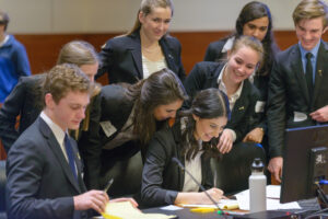 A Mock Trial team gathers around a table. They are smiling and enjoying themselves. 