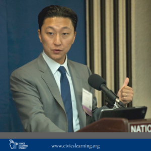 A man wearing a suit and tie speaks passionately from behind a podium